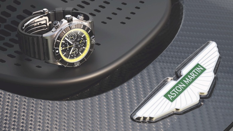 A Breitling watch next to an Aston Martin badge