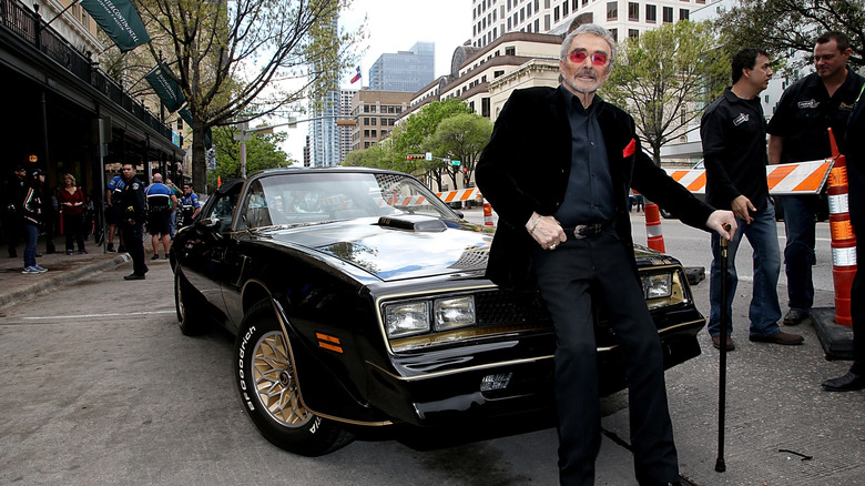 Burt Reynolds posing with a Trans Am in later life