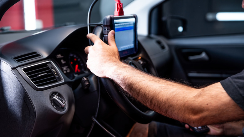 A mechanic physically updating a car via a scan tool