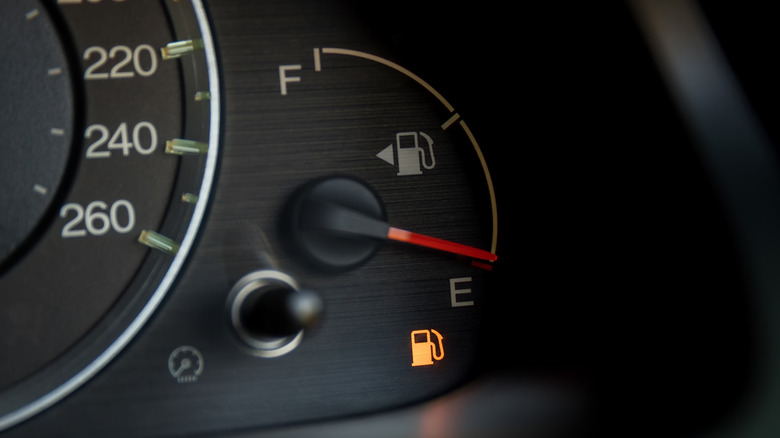 A car's fuel gauge with the fuel warning light illuminated