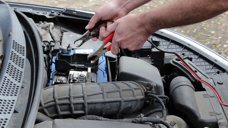 Positive and negative leads being connected to a car battery