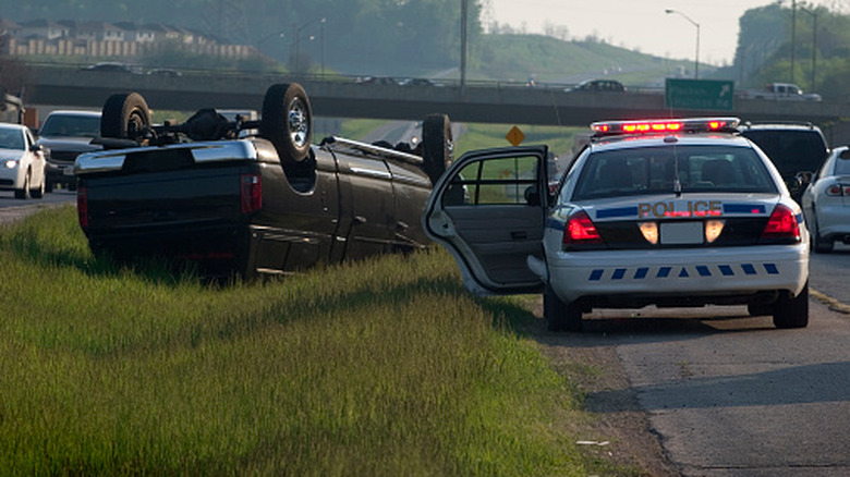 An overturned vehicle on the highway with a police car nearby