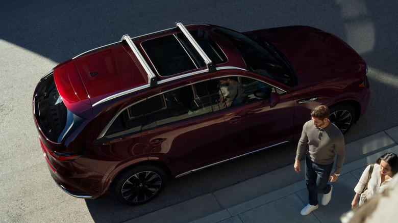 A dark red Mazda CX-90 and a couple