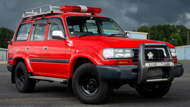 The red Land Cruiser 80 Series with a siren and emergency lights parked outside in cloudy weather