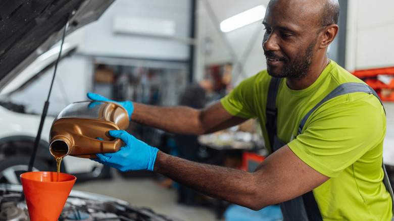 A mechanic pouring oil into an engine