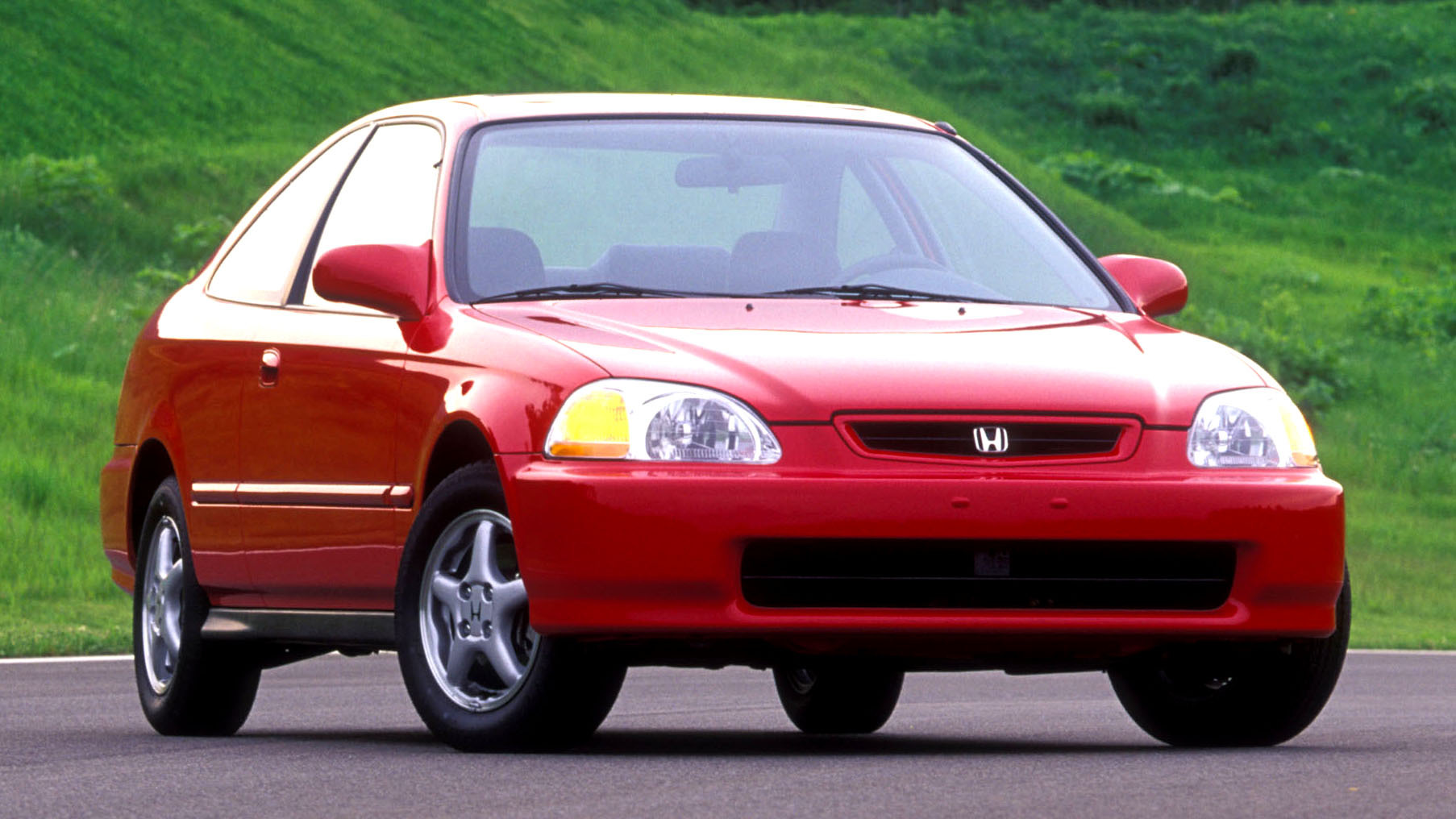 Un’auto di serie del 2000, con dettagli di colore e accessori, parcheggiata in un’area di mostra, circondata da persone che la osservano